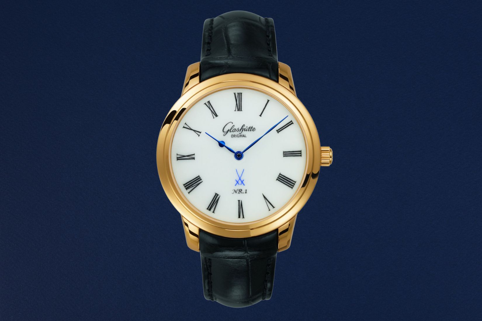 Orologio Glashütte Original Senator Meissen NR.1 con quadrante in autentica porcellana bianca Meissen, logo spade incrociate blu, cassa in oro giallo e cinturino in pelle nera, su sfondo blu profondo.