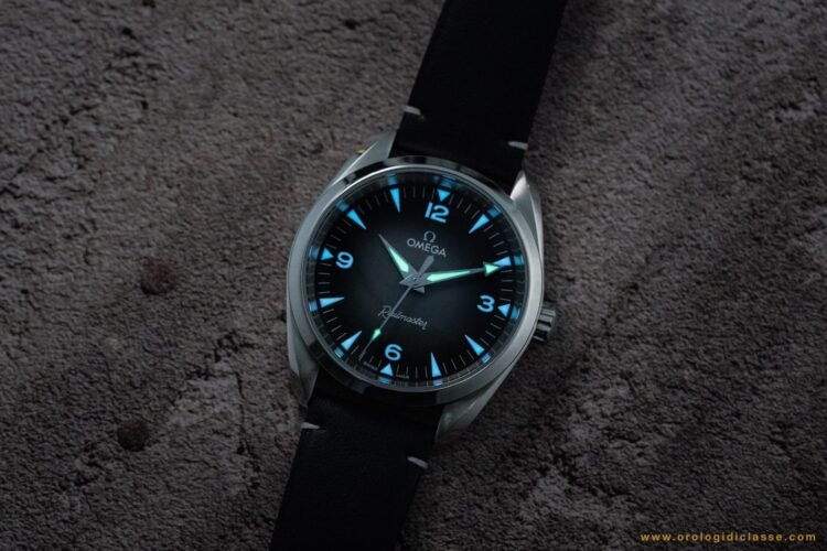 Omega Railmaster 2025 al buio: Super-LumiNova bicolore con lancette (ore, minuti, secondi) verdi e indici delle ore blu per una leggibilità ottimale.
