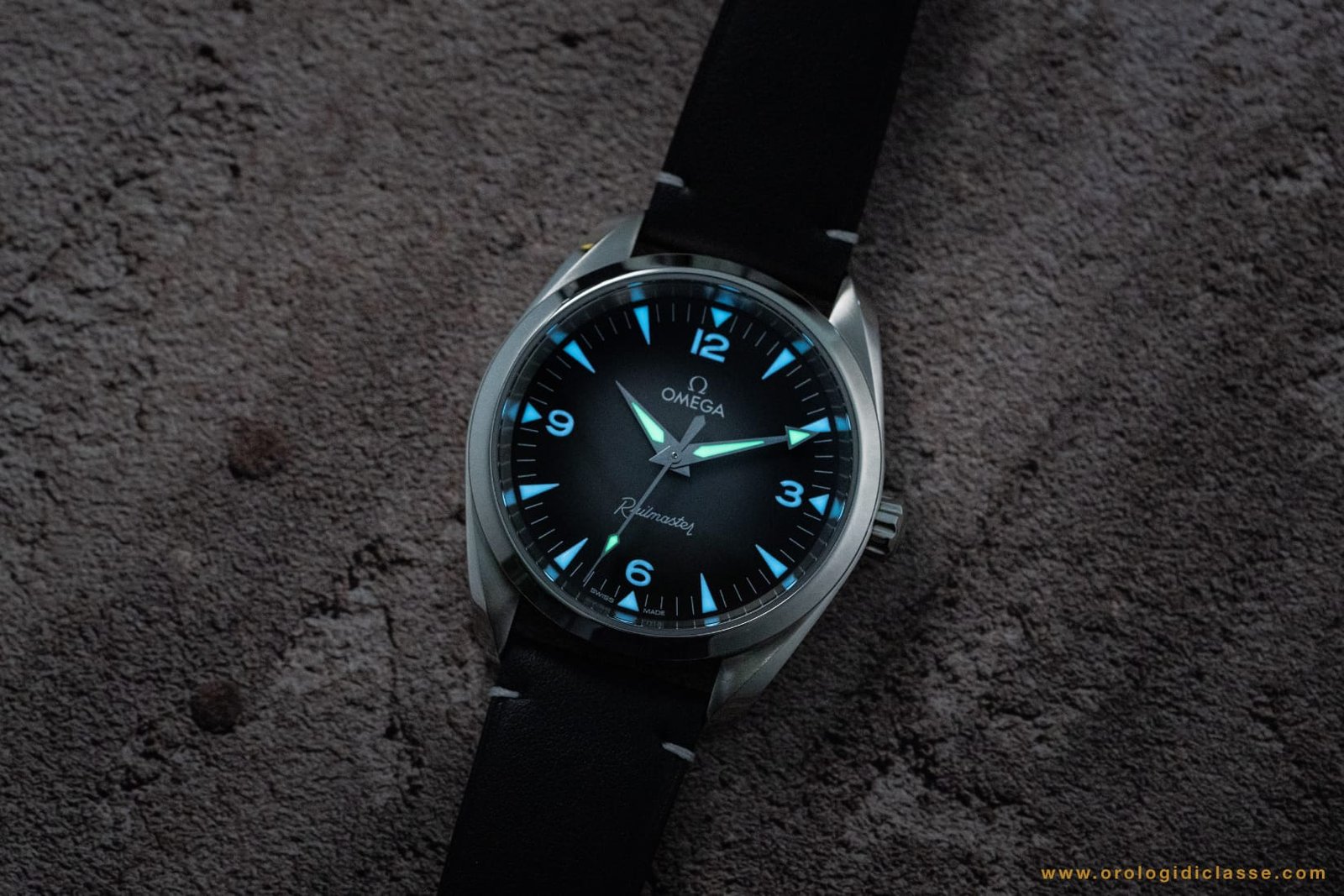 Omega Railmaster 2025 al buio: Super-LumiNova bicolore con lancette (ore, minuti, secondi) verdi e indici delle ore blu per una leggibilità ottimale.