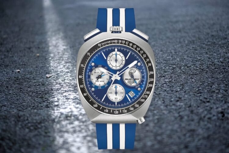Bulova Shelby 150th Racer Chronograph (98B452) – cover su asfalto Bulova Shelby Racer Chronograph 150th (98B452) bullhead, quadrante blu e cinturino a strisce, su sfondo asfalto bagnato