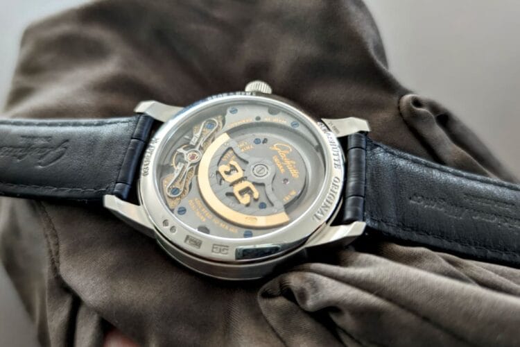Calibro 92 dal vivo: il nuovo movimento di manifattura Glashütte Original visibile dal fondello del PanoMaticLunar Anniversary Edition Fondello trasparente del Glashütte Original PanoMaticLunar Anniversary Edition che mostra il calibro 92 di manifattura con platina a tre quarti, coste di Glashütte e rotore dorato del movimento automatico