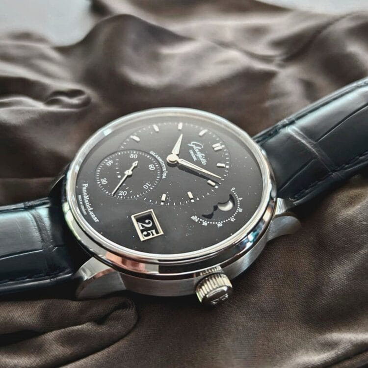 Profilo PanoMaticLunar Anniversary: eleganza della cassa in platino e dettagli della corona nel test dal vivo Vista di profilo del Glashütte Original PanoMaticLunar Anniversary Edition che evidenzia la cassa in platino da 40mm, la corona scanalata e il quadrante in avventurina blu con Data Panoramica e fasi lunari