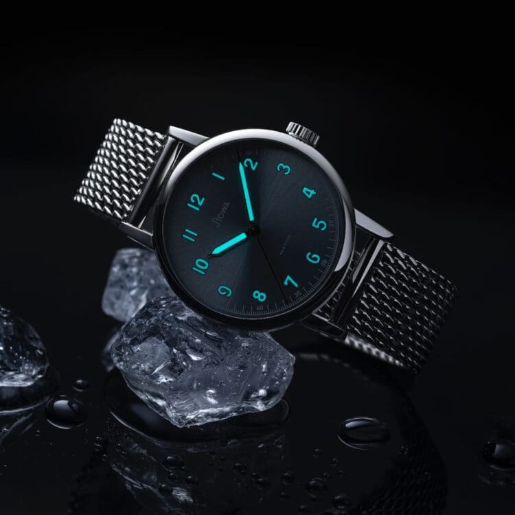 Stowa Partitio Ice Blue - Luminescenza Superluminova BGW9 blu-verde su quadrante e lancette Stowa Partitio Ice Blue al buio con Superluminova BGW9 attivo su numeri arabi e lancette, bracciale milanese su ghiaccio