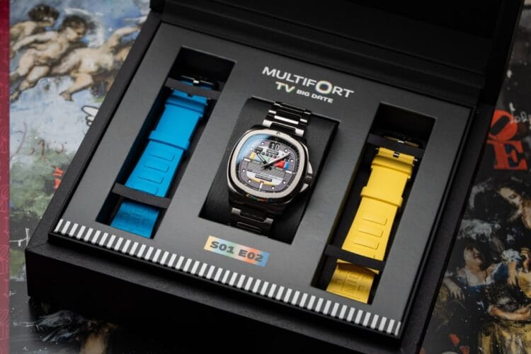 La confezione speciale del S01E02 con i cinturini blu e giallo La confezione speciale del Mido Multifort TV Big Date S01E02, che mostra l'orologio al centro con i due cinturini in gomma aggiuntivi, blu e giallo, ai lati.