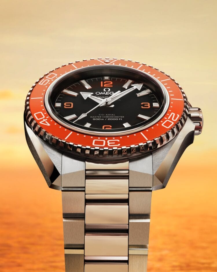 Omega Planet Ocean 2025 modello arancione con ghiera in ceramica [ZrO2] e quadrante nero opaco, mostrato sul bracciale in acciaio.