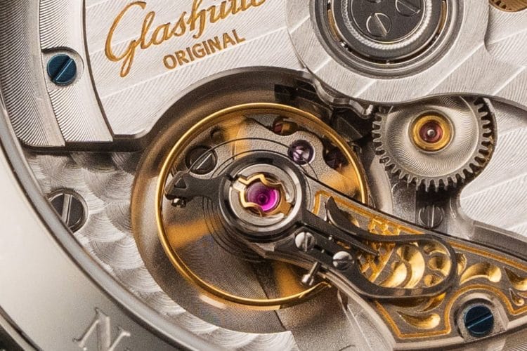 Dettaglio macro del bilanciere in movimento Fotografia macro del bilanciere di un orologio automatico Glashūtte Original Cakibro 36 in movimento, che evidenzia la complessità meccanica e la sensibilità alla gravità.