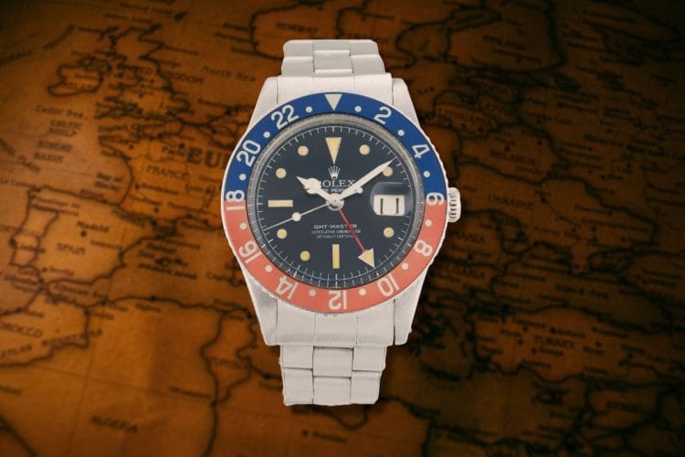 Rolex GMT-Master 6542 Pepsi: il primo grande GMT da viaggio Orologio Rolex GMT-Master ref. 6542 con ghiera Pepsi rosso e blu su sfondo di mappa geografica vintage.