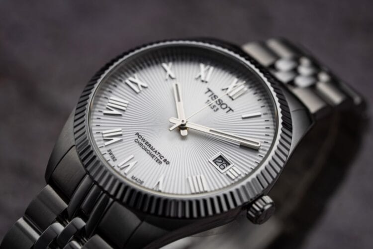 Tissot Ballade COSC - Dettaglio quadrante con certificazione Chronometer visibile Dettaglio quadrante Tissot Ballade COSC con scritta Powermatic 80 Chronometer, numeri romani applicati, motivo soleil a raggiera, lunetta zigrinata e finestra data grande.