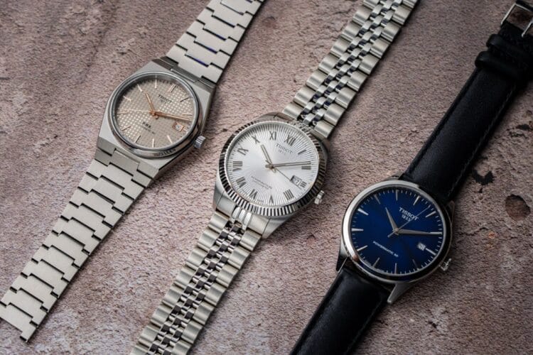 Confronto Tissot Ballade COSC, PRX Titanium e Classic Dream Powermatic 80 Tissot Ballade COSC con lunetta zigrinata e bracciale cinque maglie, Tissot PRX Titanium con quadrante petite tapisserie e Tissot Classic Dream con quadrante blu e cinturino in pelle a confronto.