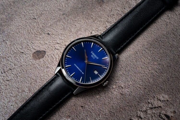 Tissot Classic Dream Powermatic 80 Tissot Classic Dream Powermatic 80 con quadrante blu soleil, indici sfaccettati, lancette dauphine dorate, finestra data a ore 3 e cinturino in pelle nera.