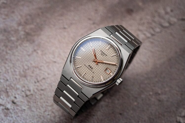 Tissot PRX Titanium 38mm - Quadrante petite tapisserie antracite con finiture color oro rosa Tissot PRX Titanium 38mm con quadrante antracite petite tapisserie, lancette e indici applicati in PVD oro rosa, bracciale integrato in titanio spazzolato e lucido.