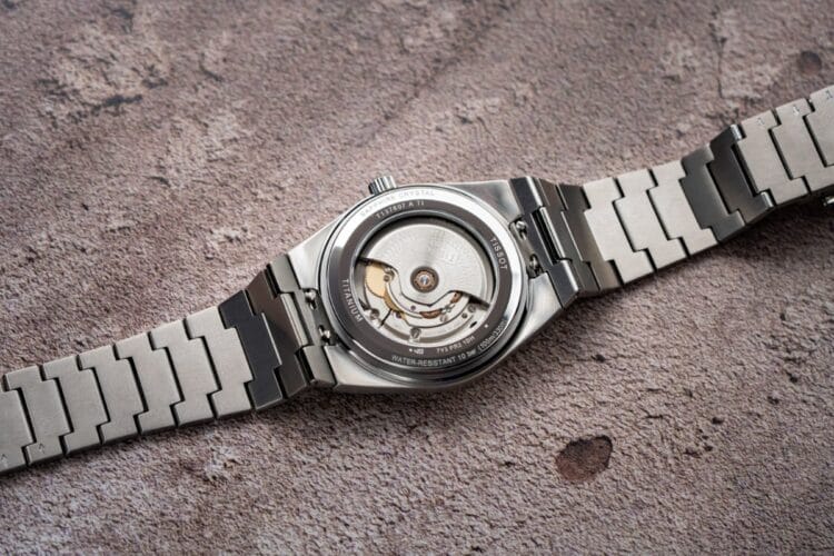 Tissot PRX Titanium - Movimento Powermatic 80 Elaborated con decorazione Vague du temps Fondello trasparente Tissot PRX Titanium con movimento Powermatic 80 Elaborated, massa oscillante decorata motivo Vague du temps, bracciale integrato in titanio.