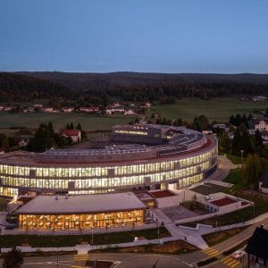 La nuova manifattura Arc di Audemars Piguet a Le Brassus: edificio curvo da 23.700 m² illuminato al tramonto nella Vallée de Joux.