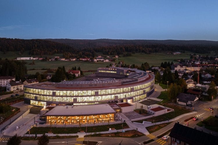 Manifattura Arc Audemars Piguet - Le Brassus, Vallée de Joux La nuova manifattura Arc di Audemars Piguet a Le Brassus: edificio curvo da 23.700 m² illuminato al tramonto nella Vallée de Joux.