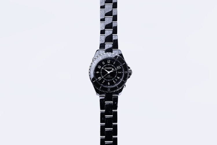 Orologio in ceramica nera circondato da gocce d'acqua, richiamo all'elemento marino.