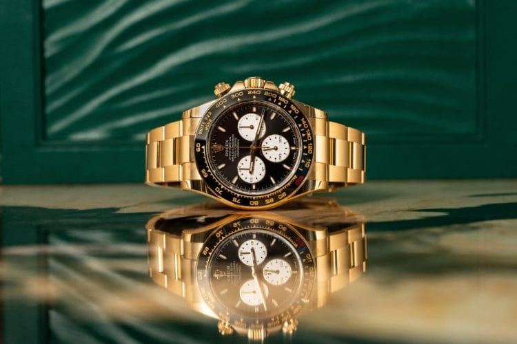 Rolex Daytona Le Mans Oro Giallo - Migliori 50 Marchi di Orologi del 2025: Rapporto Morgan Stanley Un esclusivo orologio Rolex Daytona Le Mans in oro giallo 18k su superficie riflettente, scelto come simbolo dell'analisi sui migliori 50 marchi di orologi del 2025 presentata nel rapporto Morgan Stanley.