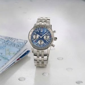 Sinn 903 Ti II Anniversary con quadrante blu, regolo calcolatore e bracciale in titanio Grado 5 accanto a una mappa.