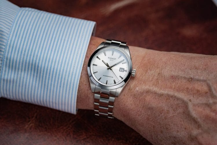 Tissot Gentleman 38 mm: Wrist-shot e vestibilità con camicia Prova al polso del Tissot Gentleman 38 mm con quadrante Silver. L'orologio scivola perfettamente sotto il polsino di una camicia a righe, mostrando proporzioni ideali e un'eleganza versatile per tutti i giorni.