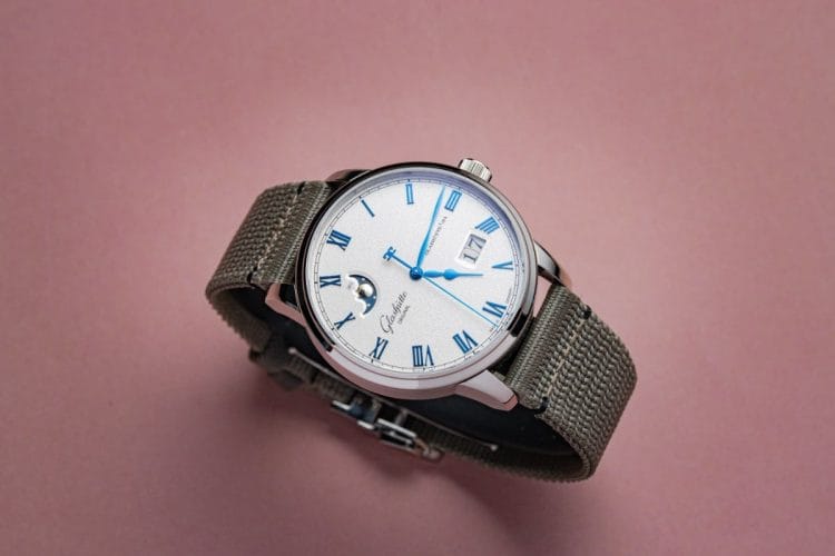 Senator Excellence con cinturino in tessuto sintetico – 90 grammi al polso Glashütte Original Senator Excellence Panorama Date Moon Phase con cinturino in tessuto sintetico grigio, vista dall'alto con angolo obliquo.