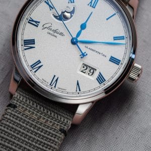 Glashütte Original Senator Excellence Panorama Date Moon Phase con cinturino in tessuto sintetico appoggiato su panno di lino grigio.