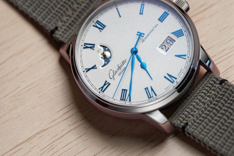 Data Panoramica e fasi lunari del Senator Excellence – dettaglio quadrante Quadrante del Senator Excellence Panorama Date Moon Phase con lancette azzurrate, fasi lunari e Grande Data visibili, su piano in legno chiaro.