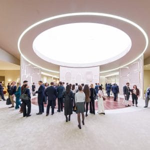 Interno del padiglione al Palexpo di Ginevra durante il Day 3 di Watches and Wonders 2026: visitatori e giornalisti nel corridoio centrale con skylight circolare.