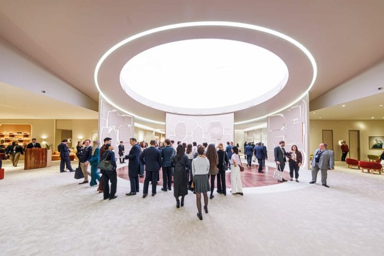 Interno del padiglione al Palexpo di Ginevra durante il Day 3 di Watches and Wonders 2026: visitatori e giornalisti nel corridoio centrale con skylight circolare.