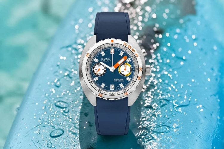Doxa Sub 200 T.Graph II Caribbean con cinturino caucciù tono su tono Doxa Sub 200 T.Graph II Caribbean su tavola da surf bagnata con acqua turchese caraibica, orologio da mare estate 2026
