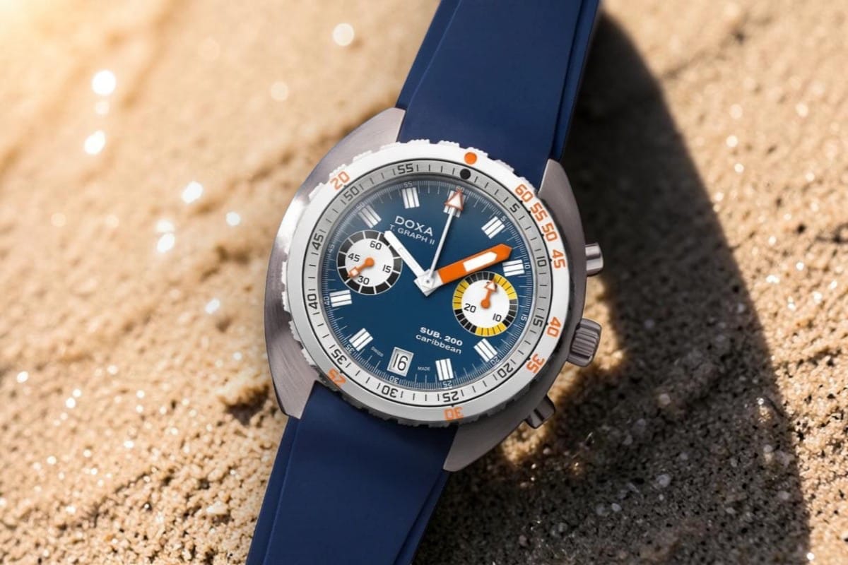 Doxa Sub 200 T.Graph II Caribbean - orologio da mare estate 2026 Doxa Sub 200 T.Graph II Caribbean su sabbia bagnata illuminata dal sole, orologio subacqueo estate 2026