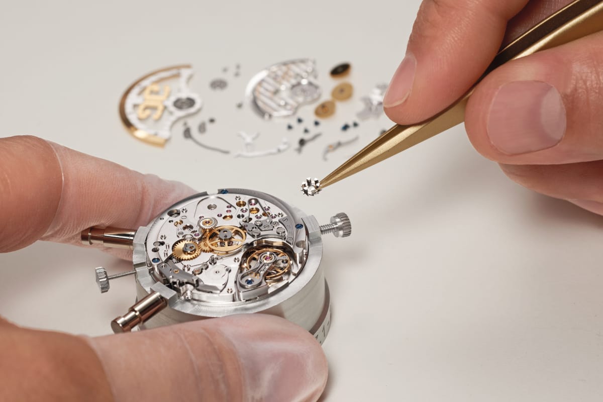 Orologiaio Glashütte Original mentre posiziona la ruota a colonne del Calibro 37 con le pinzette durante l'assemblaggio