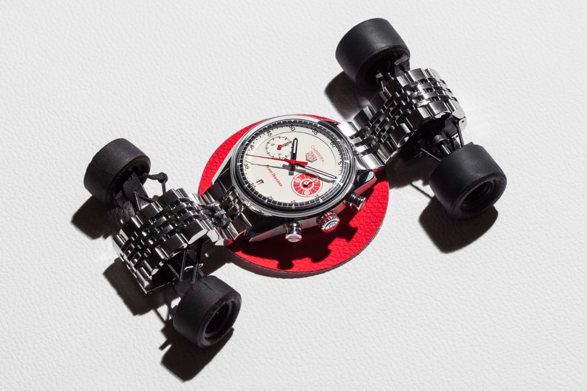 TAG Heuer Carrera Chronograph x Team Ikuzawa - still life con monoposto da corsa in scala TAG Heuer Carrera Chronograph x Team Ikuzawa su disco rosso integrato in una monoposto giocattolo, ripreso dall'alto