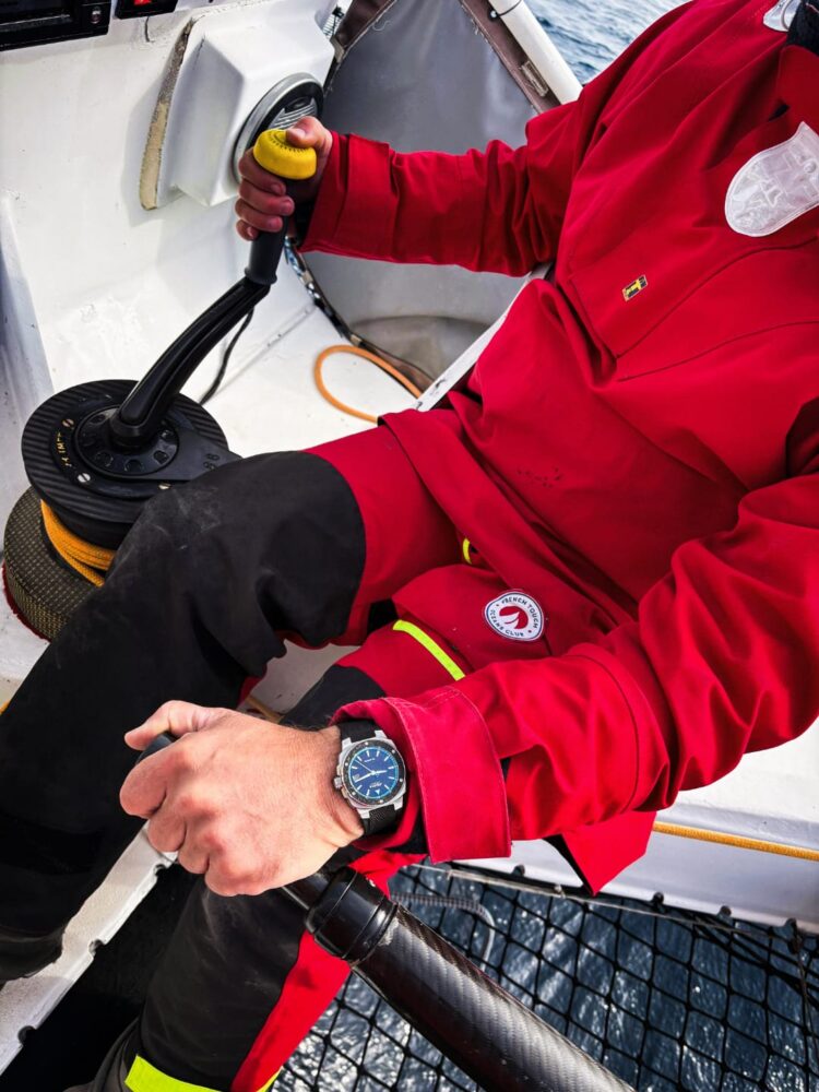 Eric Péron in navigazione durante la Route du Rhum con un orologio Alpina al polso.