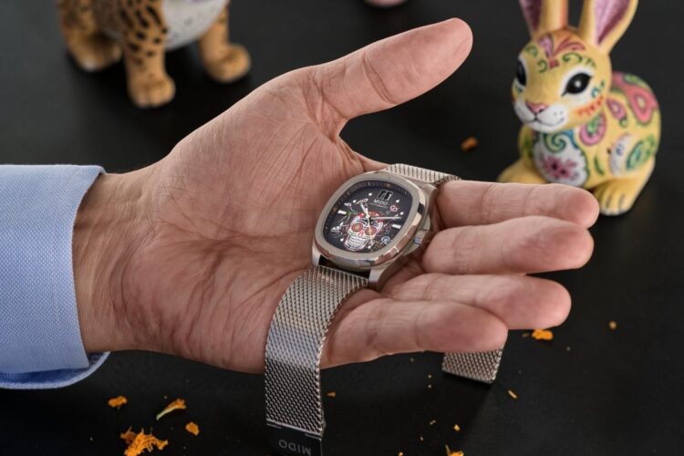 Mido Alebrijes con bracciale milanese Mido Multifort TV Alebrijes tenuto in mano con il bracciale in maglia milanese.