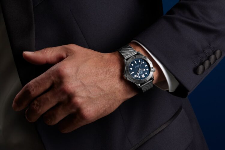 Nuovo Omega Seamaster Diver 300M James Bond in acciaio al polso, con quadrante blu a onde, lunetta in titanio e bracciale mesh.